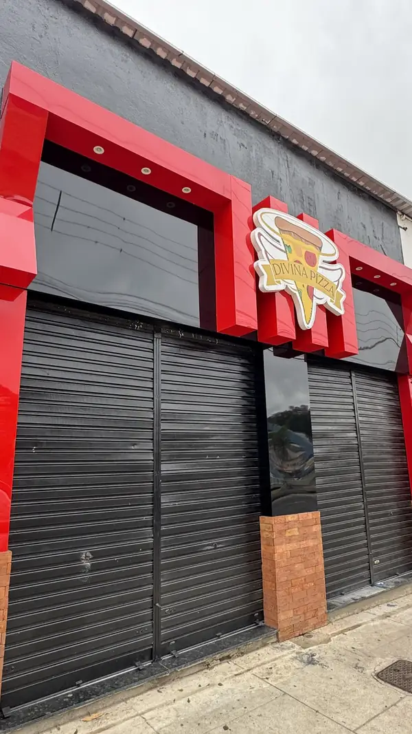 Fachada em ACM vermelho e preto da Divina Pizza, com a logo recortada em destaque, feita pela DPrint