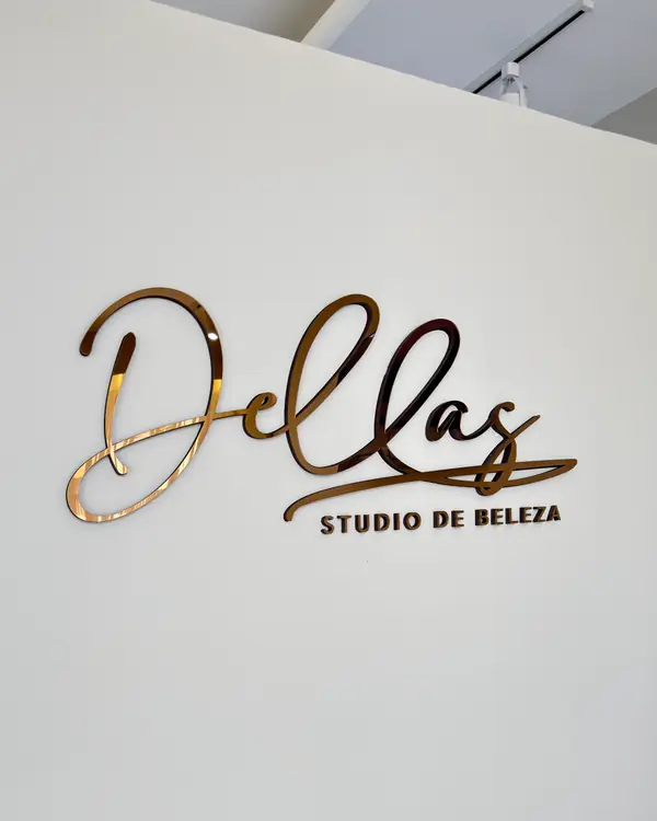 Logo do Dellas Studio de Beleza em acrílico dourado espelhado