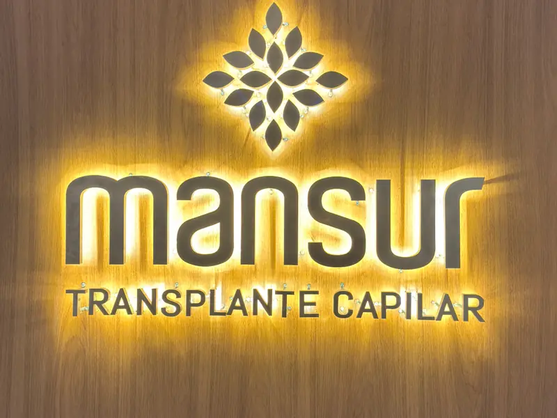 Logo da Mansur Transplante Capilar com LED por trás, iluminando a parede